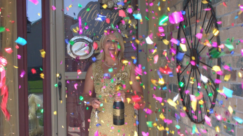 woman on front porch celebrating with champagne and confetti blowing
