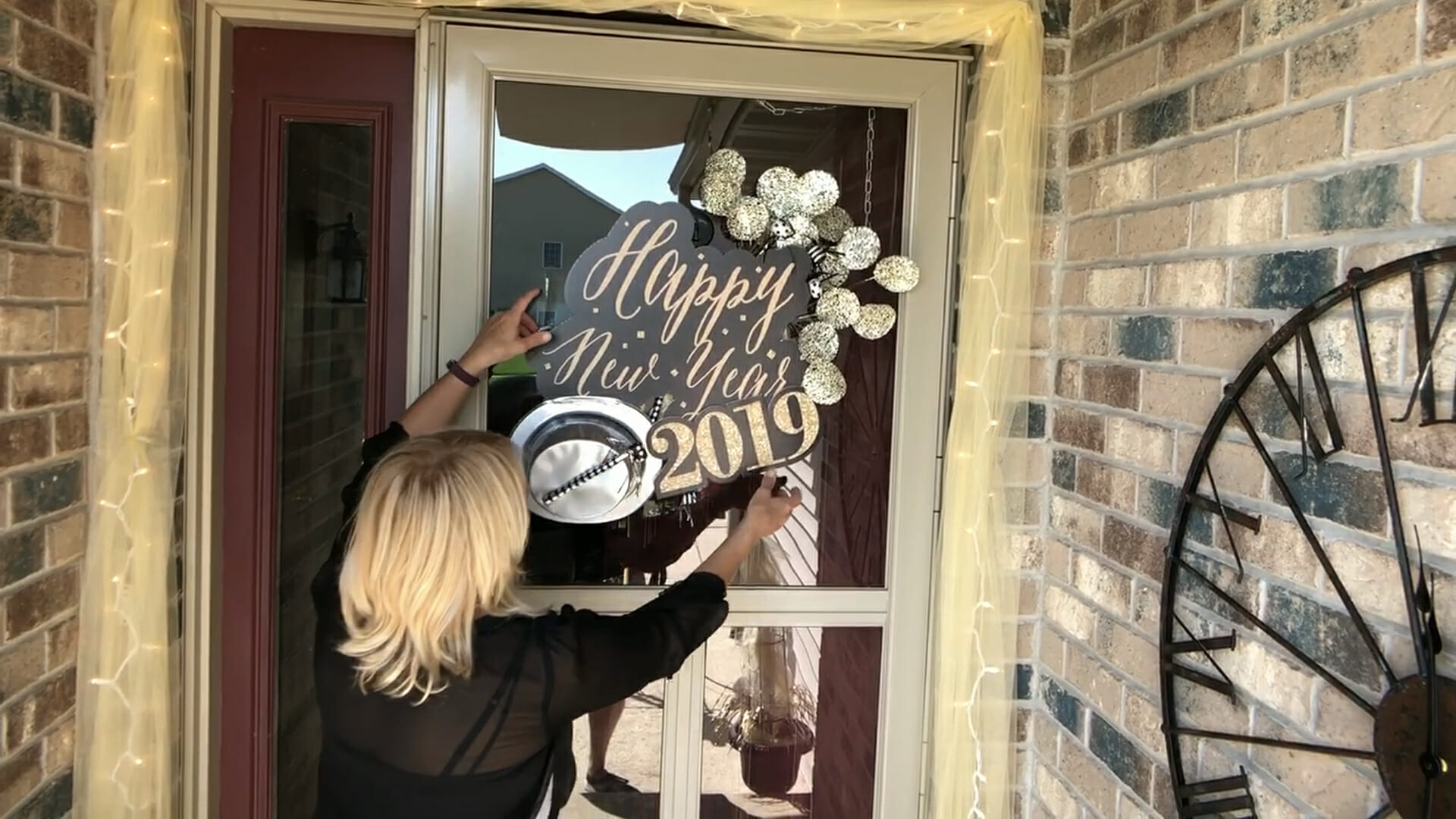 woman hanging Happy New Year 2019 décor on front door