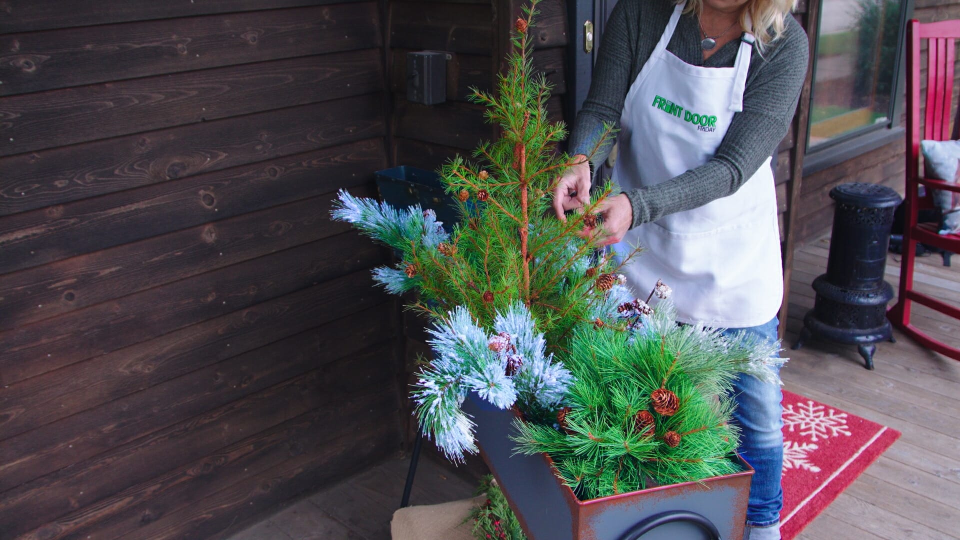 woman arranging evergreens in a metal flower box to create a winter theme décor