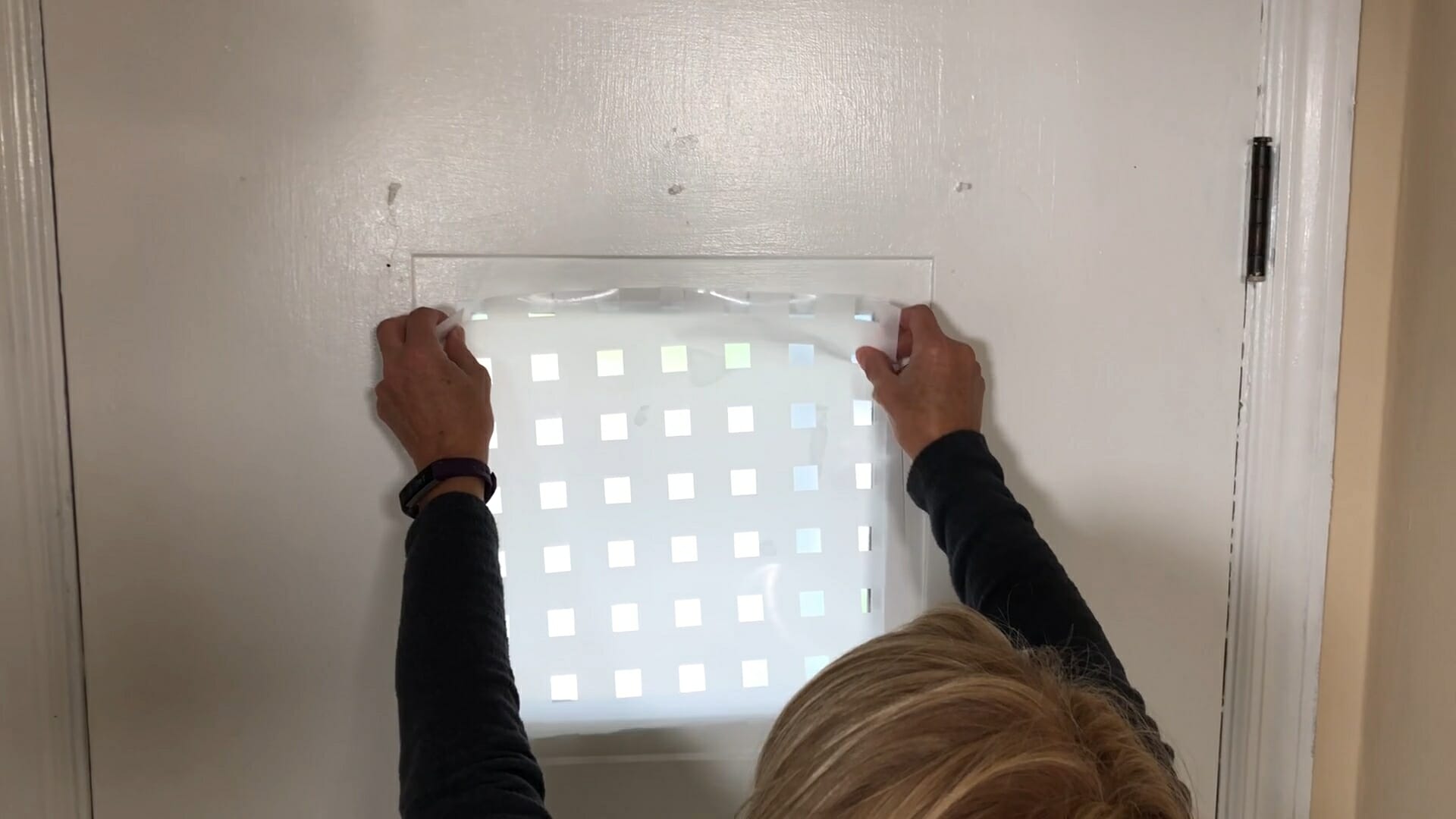 woman applying privacy paper to window