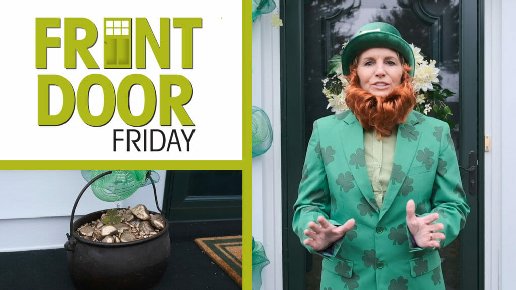 woman standing on front porch dressed as a leprechaun with a pot of gold