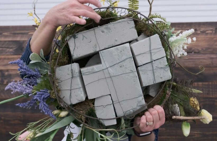 woman showing back of wreath filled with floral foam blocks