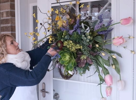 woman hanging spring foliage and tulip wreath on door