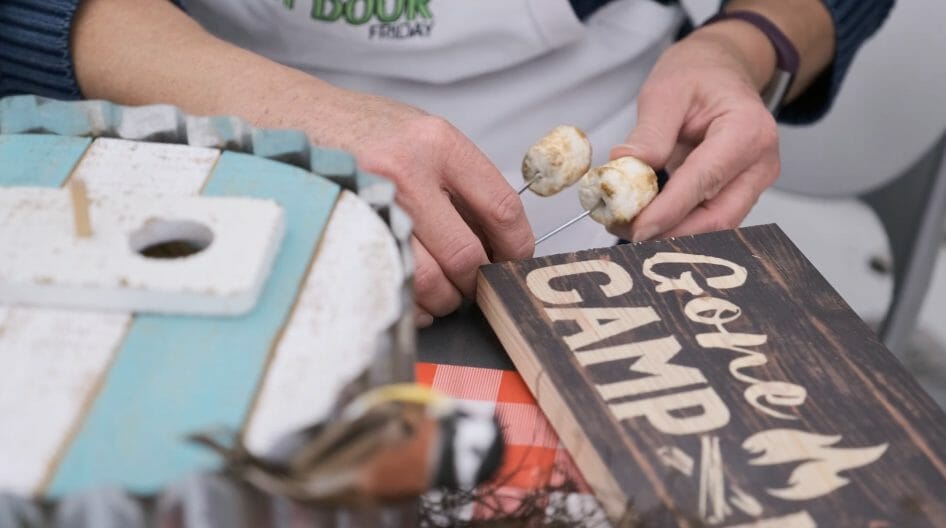 woman applying roasted marshmallows to camping themed wreath