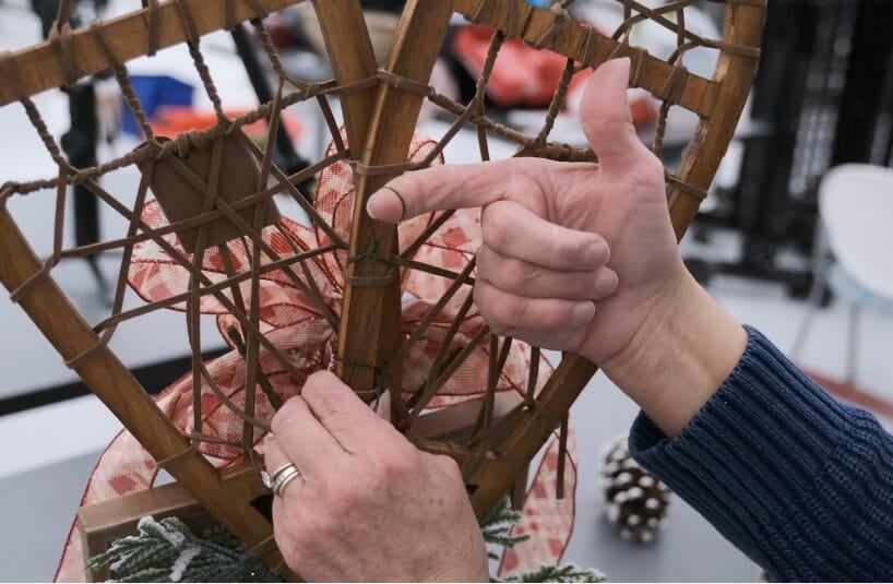 woman using wire to create hanger for wreath