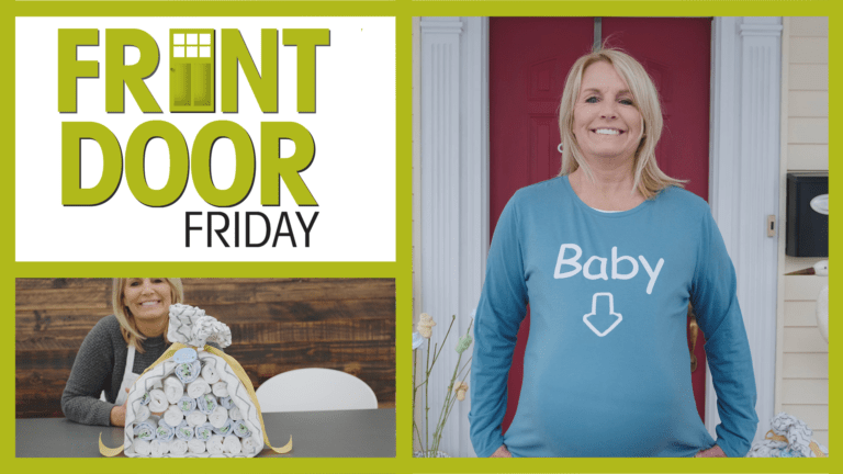 FRONT DOOR FRIDAY – A blonde woman in a blue T-shirt with Baby and an arrow, and with baby diapers rolled in a bundle.