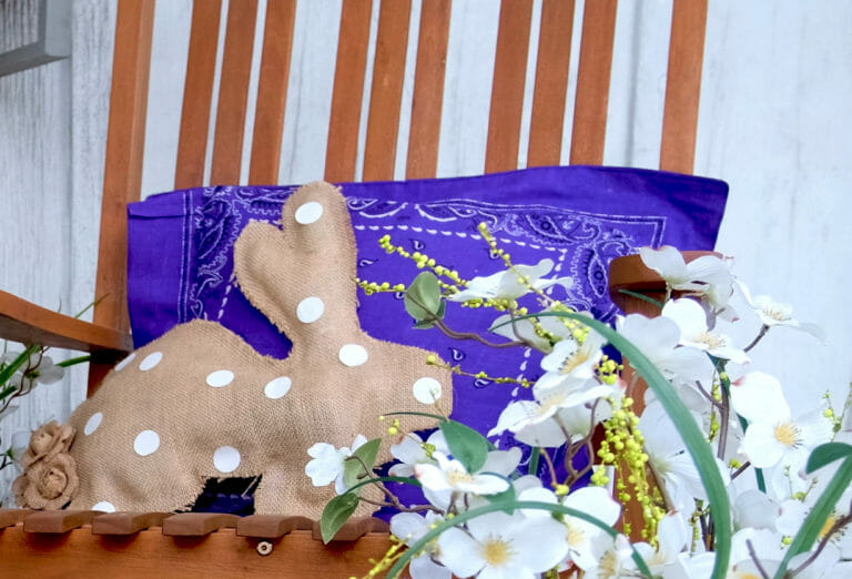 burlap and polka dot bunny and purple bandana pillow on chair with white flowers for an Spring and Easter look