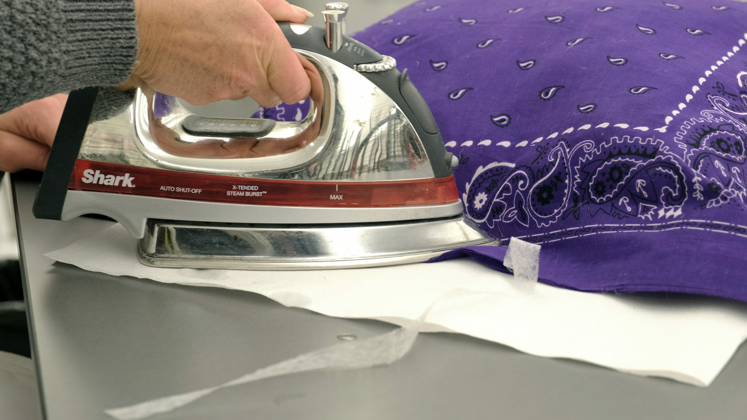 woman ironing a purple bandana pillow