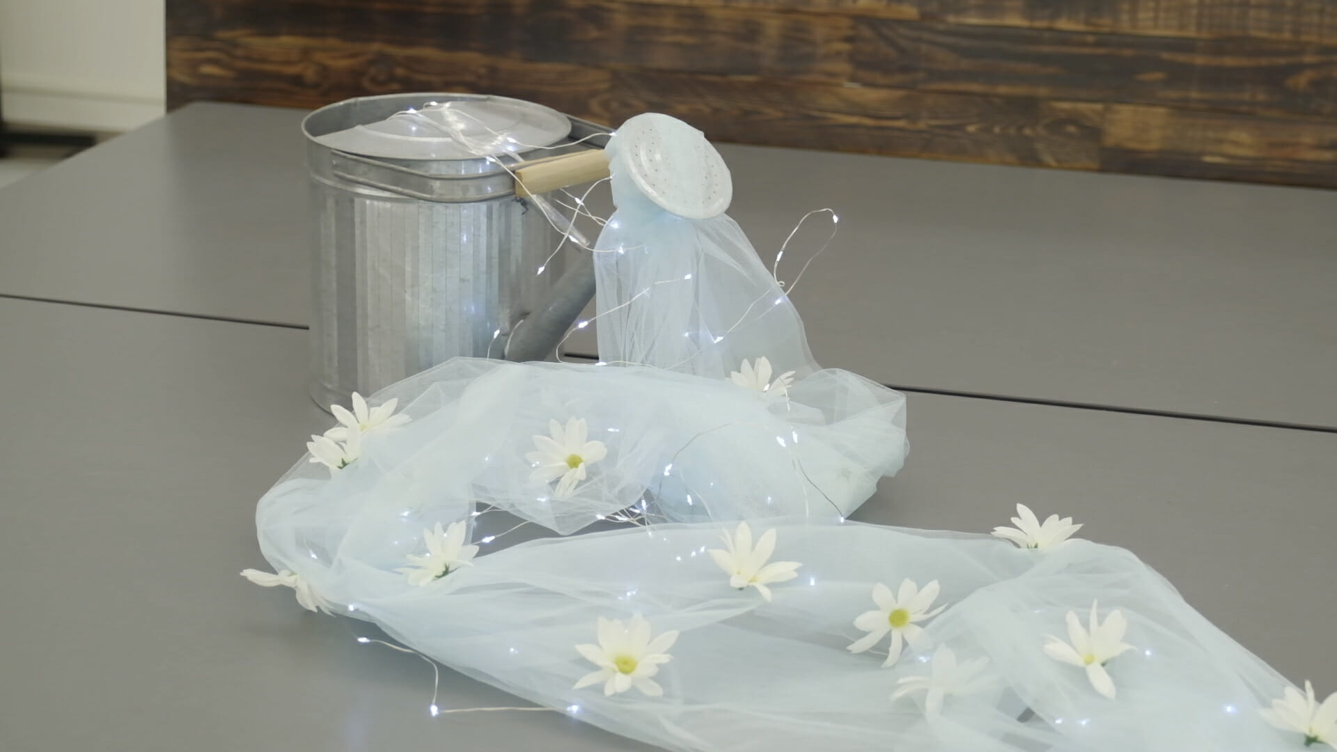 watering can with daisies lights and tulle fabric