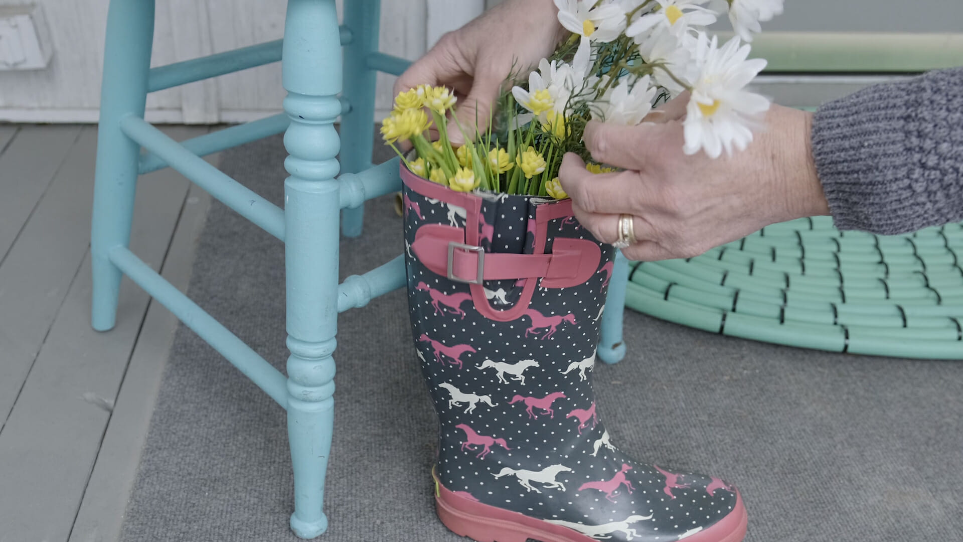 woman putting spring flowers in rubber rain boot