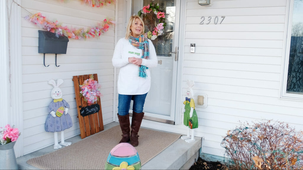 woman standing on porch with Easter egg and Easter bunny décor