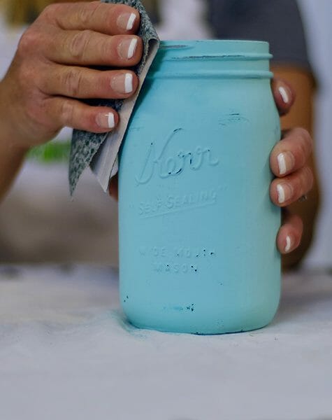 sanding a teal painted Mason jar