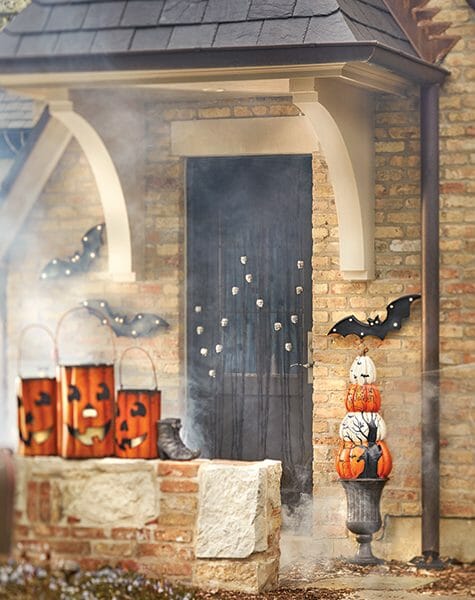 Lit bats and metal Jack-o-Lanterns, a pumpkin topiary, and a skull garland on the black front door.