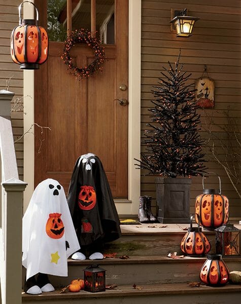 Front door with a bittersweet wreath, two ghosts in black and white, lit metal Jack-o-Lanterns, and a Halloween tree.