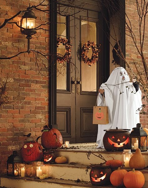 Bittersweet wreaths on brown French doors, a white ghost, pumpkins, and lit lanterns and Jack-o-Lanterns.