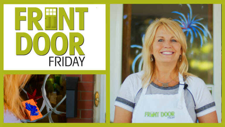 Front Door Friday – Smiling woman on a porch with Patriotic fireworks painted on the window.