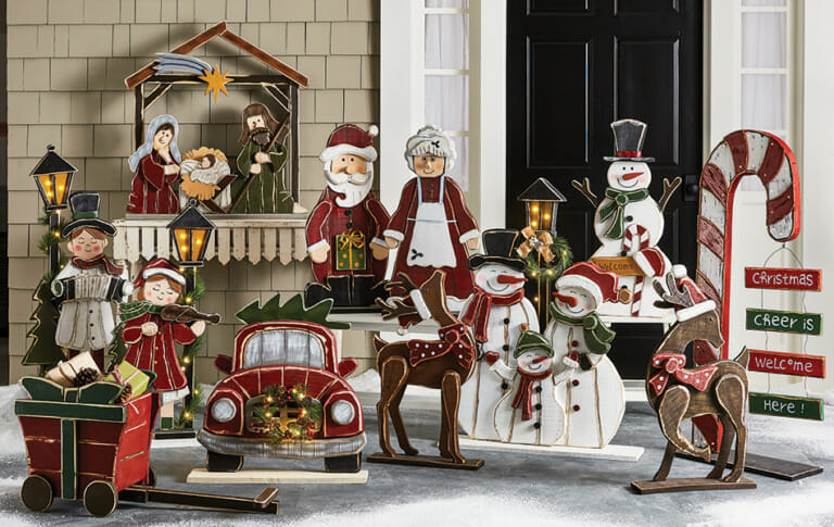 Several Winter holiday wood cutouts, including the Nativity, carolers, snowmen, a lit candy cane, deer, and Santa and Mrs.